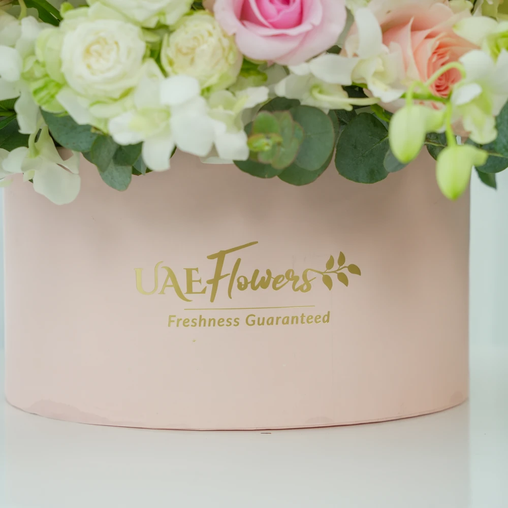 A box arrangement of 20 white orchids, 12 pink roses, 12 pink carnations and 5 white spray roses with green fillers.