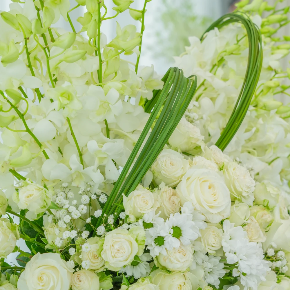 A box arrangement of 20 white orchids, 20 white roses, 5 white spray roses with white chrysanthemums and steel grass.