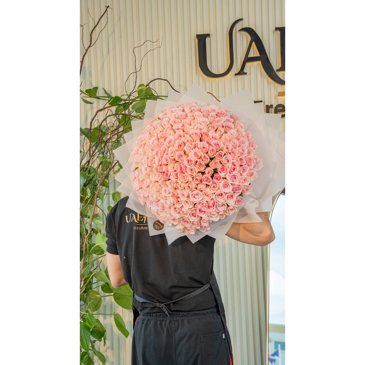 Luxurious bouquet of 200 handtied pink roses wrapped in white paper and tied with satin ribbon – elegant grand floral gift by UAE Flowers.