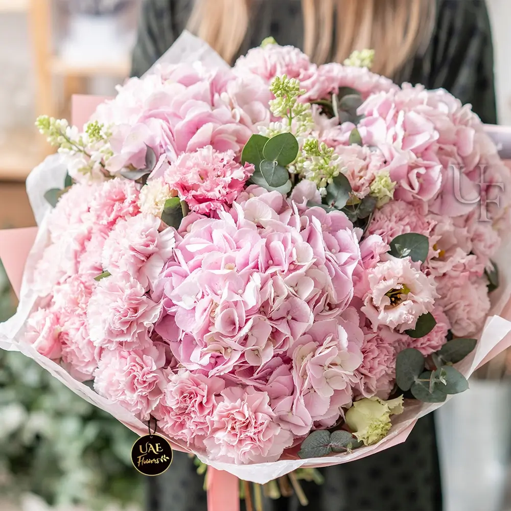 A bouquet of 4 pink hydrangeas and 30 pink carnations with fillers in pink wrapping paper tied with pink ribbon