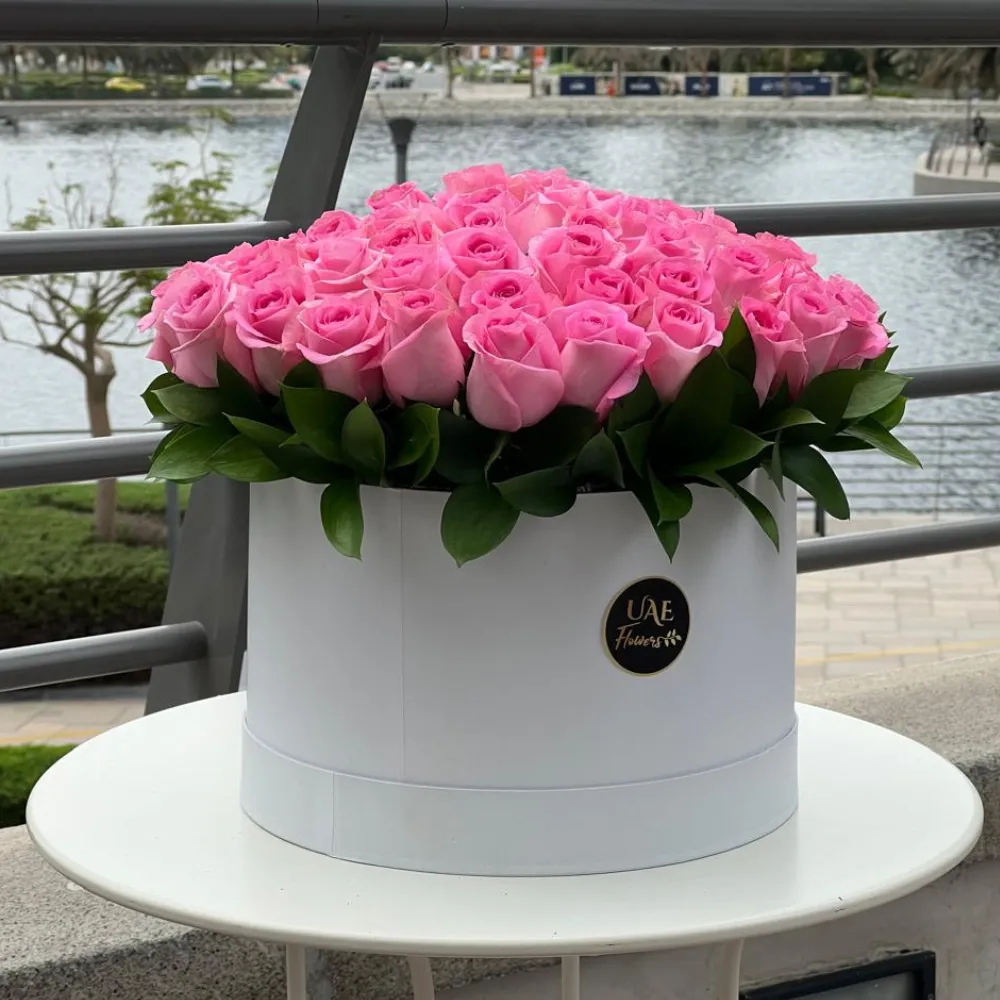 60 pink roses with green fillers arranged in a white round box