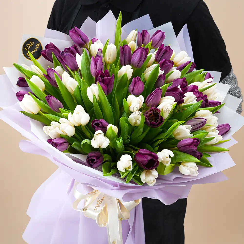 A bouquet of 40 purple & 40 white tulips with fillers in brown wrapping paper tied with white ribbon