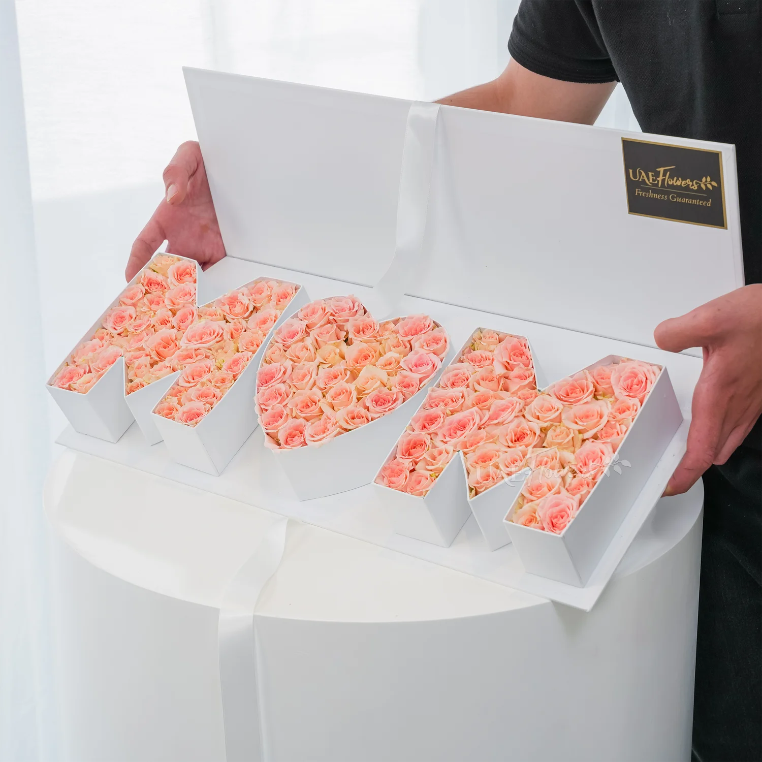 Heartfelt floral arrangement of 30 pink spray roses in a white MOM-shaped box – a perfect gift for Mother’s Day by UAE Flowers.