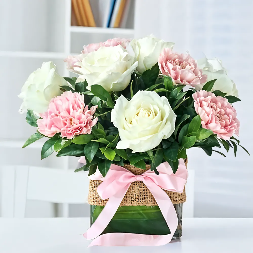 8 white roses and 6 pink carnations with green fillers arranged in a glass vase, a charming floral gift for special occasions.