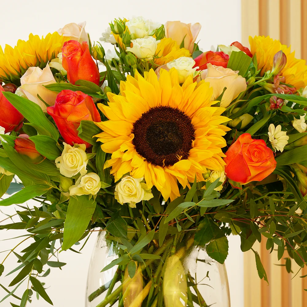5 sunflowers, 7 orange roses, 7 peach roses, 3 white spray roses, 3 red alstroemerias