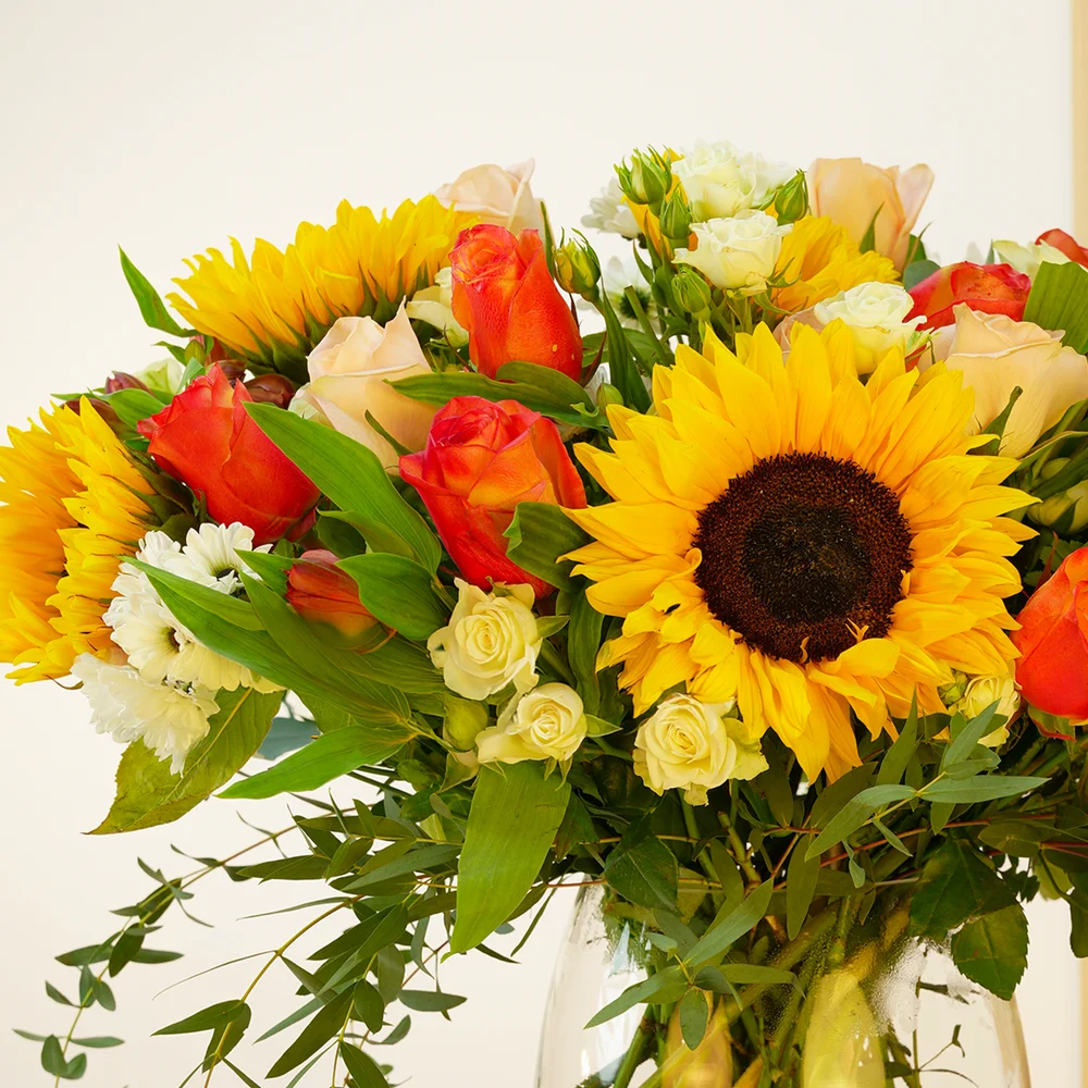 5 sunflowers, 7 orange roses, 7 peach roses, 3 white spray roses, 3 red alstroemerias