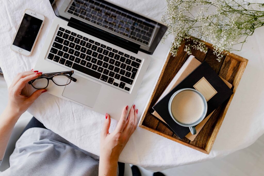 Laptop with phone, specs, and Tea on a Table